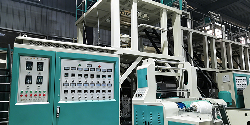 Operating mono-layer blown film machine showing extruder, die head, and forming bubble in manufacturing environment